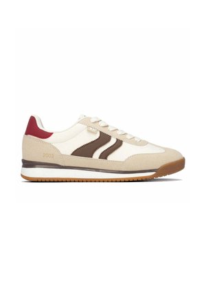 Zapatilla beige y blanca con rayas marrones, acento rojo en el talón, cordones blancos y suela de goma, mostrada de lado sobre un fondo blanco.