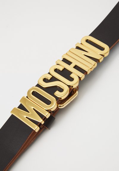 Mustmust nahkrihm laia kuldse metallist "MOSCHINO" sõlgaga. Sile tekstuur ja läikiv viimistlus, tugeva kirjatüübiga.