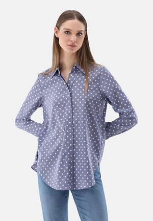 Light blue polka dot shirt with long sleeves and a button-down collar, made of smooth fabric with a relaxed, slightly curved hem.