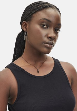 Schwarzes geripptes ärmelloses Oberteil mit rundem Ausschnitt; beinhaltet eine dünne Halskette mit einem rechteckigen Anhänger und geometrischen schwarzen Ohrringen.