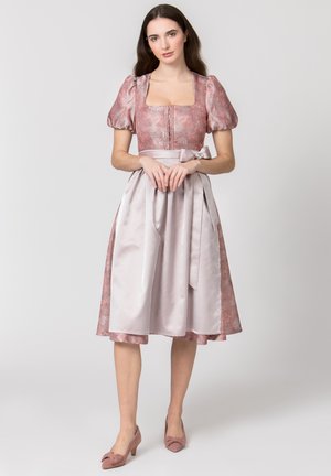 Frau trägt ein knielanges rosa Brokatkleid mit Puffärmeln und eine glänzende blassrosa Schürze, die mit einer Schleife in der Taille gebunden ist.