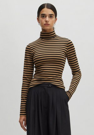 Striped turtleneck top in brown and black. Slim fit with long sleeves, soft texture, and a high collar. Paired with black pleated trousers.