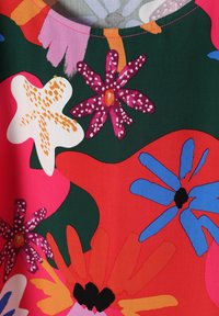 Blumenmusterstoff mit dunkelgrünem Hintergrund, versehen mit kräftigen Blumen in Pink, Weiß, Blau und Orange in unterschiedlichen Formen und Größen.