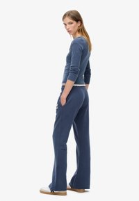 Marineblå langærmet top med en tætsiddende pasform og rund halsudskæring, parret med matchende brede sweatpants med lommer og broderede detaljer.