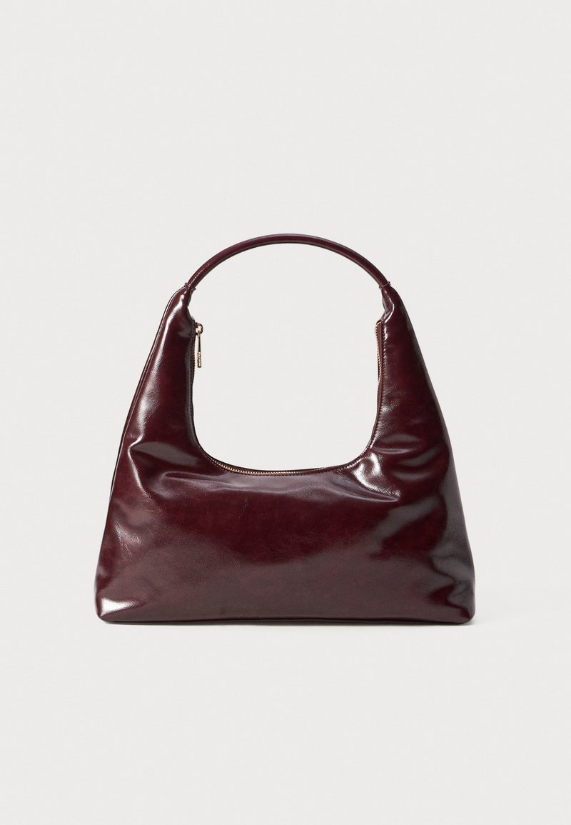 Burgundia nahast kott, millel on läikiv viimistlus, ümar käepide ja lukuotsikuga ülemine avamine; iseloomustab selle sujuv, minimalistlik disain.