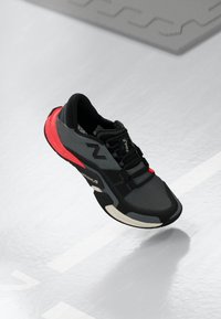 Fekete és szürke sportcipő piros részletekkel, légáteresztő hálós felsőrész, szintetikus borítások, könnyű kivitel és tartós gumitalp.