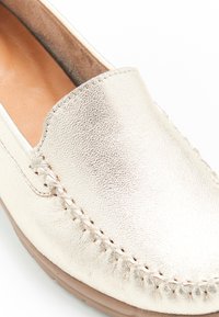 Scarpa slip-on in oro metallico con tomaia in pelle texturizzata, caratterizzata da cuciture decorative e una suola piatta e flessibile per il comfort.