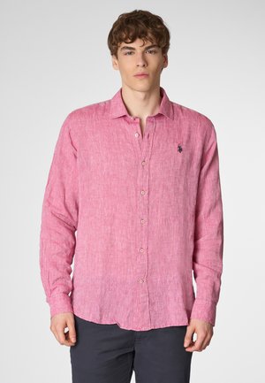 Camicia in lino rosa a maniche lunghe con una sottile trama, chiusura a bottoni e un piccolo logo sul petto, abbinata a pantaloni scuri.