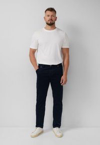 Marineblauwe corduroybroek, slim fit, gecombineerd met een witte T-shirt met ronde hals en witte sneakers. Gladde textuur, eenvoudig ontwerp en geen zichtbare patronen.
