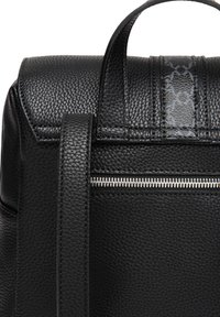 Zwarte leren rugzak met een gestructureerde afwerking, een bovenhandvat en een zilveren ritssluiting. Subtiele designaccenten op het bovenpaneel.