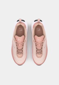 Baskets Nike Air en rose clair et beige, avec un dessus texturé, une semelle lisse, des lacets et un logo sur la languette et le côté.