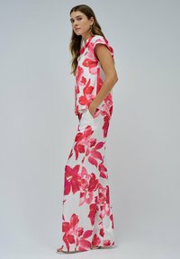 Completo floreale a due pezzi composto da un top senza maniche e pantaloni a gamba larga. Il materiale è morbido e presenta un vivace motivo floreale rosa e bianco.
