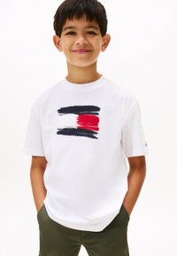 T-shirt en coton blanc avec un motif de coup de pinceau horizontal en bleu marine, blanc et rouge. Manches courtes et coupe décontractée.