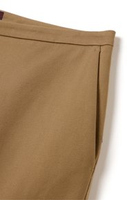 Pantalons kaki en tissu texturé, présentant un design à jambe droite et des détails de couture discrets le long de la taille et des coutures latérales.