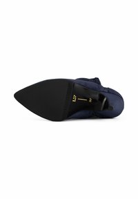 Chaussure à talon haut en suède bleu marine avec un bout pointu, dotée d'une semelle lisse noire et d'un petit tirant au niveau du talon pour un enfilage facile. Taille marquée comme 37.