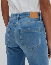 Light blue denim jeans with a straight cut, leather label on waistband, two back pockets, and subtle fading on fabric texture.