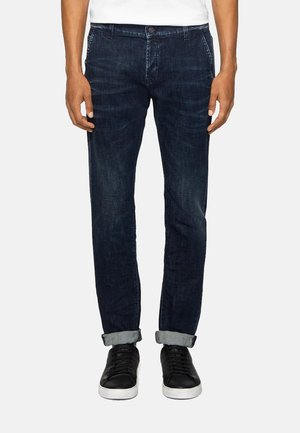 Jeans in denim blu scuro con vestibilità slim, dotati di chiusura a bottone, tasche frontali e orli arrotolati. Abbinate a sneakers nere.