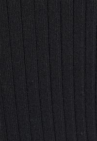 Tessuto nero a coste con una superficie texture, caratterizzato da linee verticali e un materiale morbido e elasticizzato.