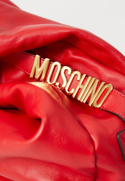 Geantă roșie din piele cu o textură moale, având un logo auriu proeminent "MOSCHINO" în partea de sus și detalii din țesătură netedă, pliate.