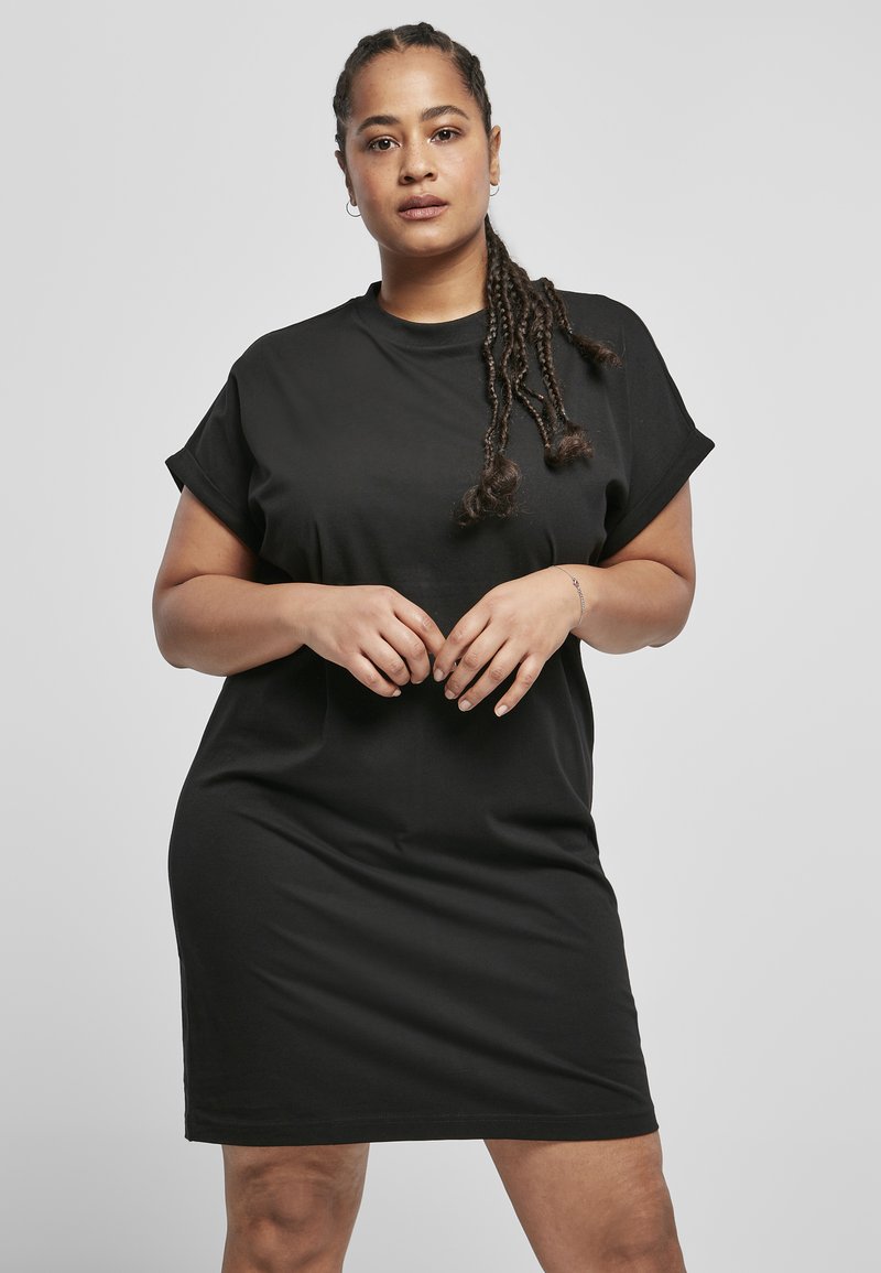 Robe t-shirt noire à manches courtes en tissu doux. Coupe décontractée avec un col rond et une longueur au-dessus du genou. Design minimaliste.