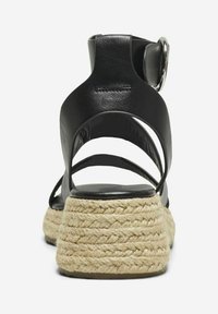 Svarta lädersandaler med espadrille-design och flätad jute-klack, med flera remmar och en detaljerad metallspänne.
