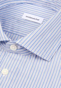 Chemise à rayures bleues et blanches avec des boutons blancs et une étiquette de marque « seidensticker » visible à l'intérieur du col.
