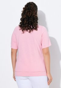 Lyserød T-shirt med korte ærmer og afslappet pasform, lavet af blødt materiale, med en rund halsudskæring og en lige kant.