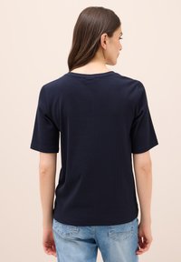 Námořnická modrá bavlněná tričko s kulatým výstřihem a krátkými rukávy, s uvolněným střihem a minimálními švy na zadní straně.
