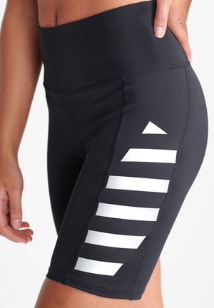 Shorts de sport noirs en tissu extensible, avec une taille haute. Soulignés par des rayures géométriques blanches le long du côté.