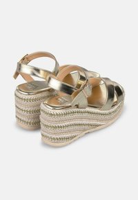 Gouden metallic platform sandalen met een gevlochten jute wiggenhak, gekruiste bandjes en een verstelbare enkelgesp. Glad textuur.