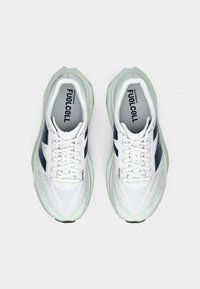 White athletic shoes with mint green accents. Mesh upper with textured patterns, laces, and a cushioned sole labeled “FuelCell.”