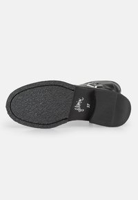 Suela de zapato negra con superficie de goma texturizada, punta redondeada y tacón ligero. Presenta el nombre de la marca y la talla impresos en el interior del tacón.