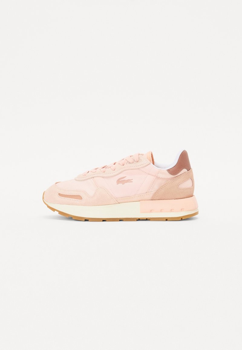 Baskets basses rose clair avec des panneaux en daim et en tissu, semelle en caoutchouc et petit logo crocodile sur le côté.