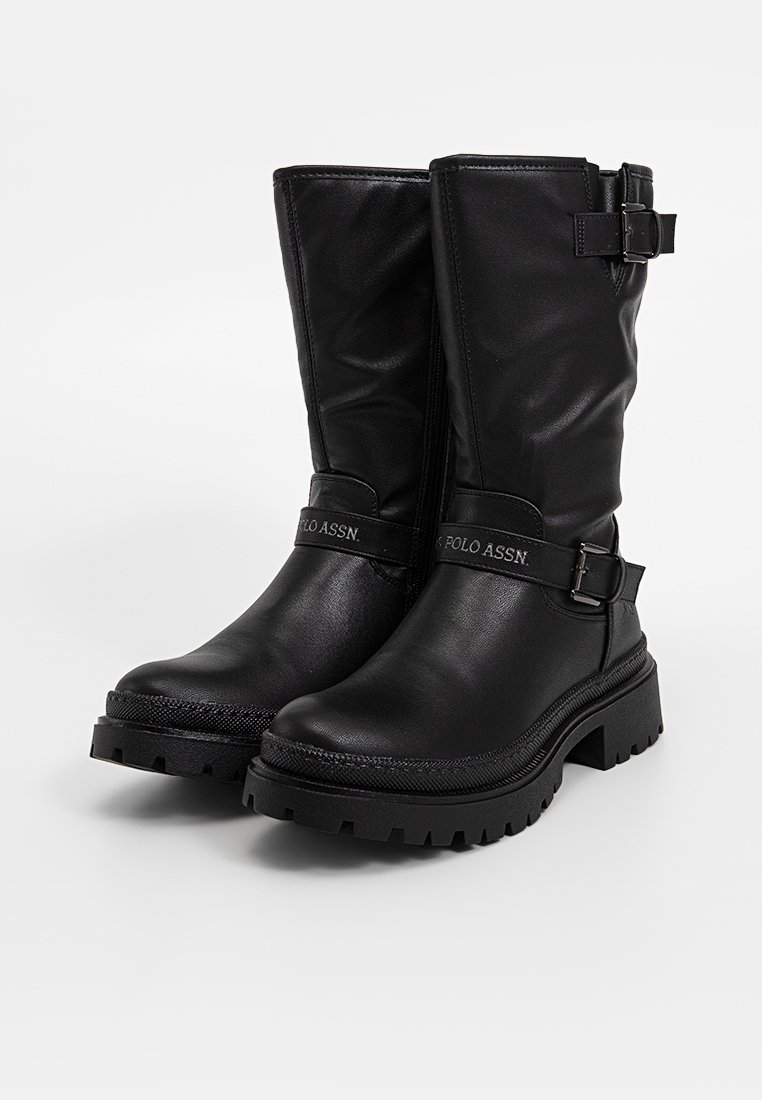 Stivaletti neri in pelle con finitura lucida, dotati di un accentuato cinturino laterale e suola in gomma textured per una migliore aderenza.