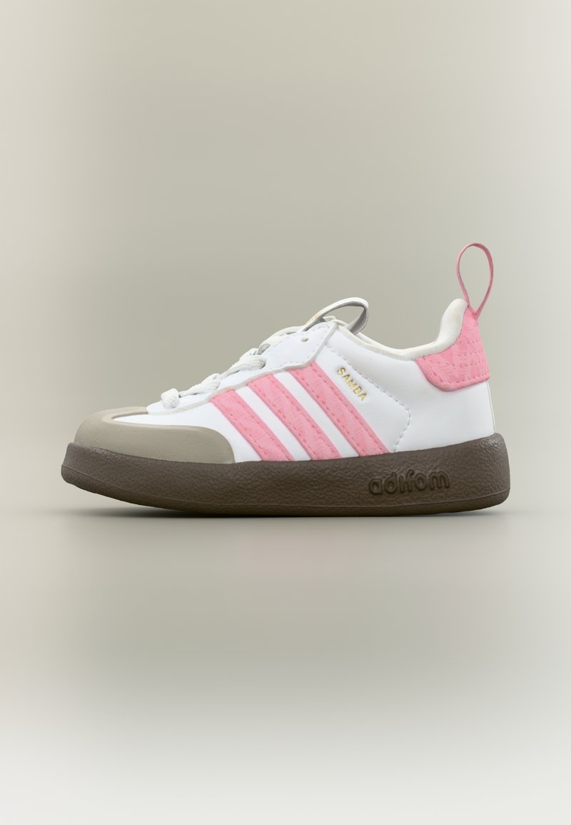 Άσπρο αθλητικό παπούτσι με ροζ ρίγες, μπεζ κάλυμμα δακτύλων και καφέ υφή σόλας. Διαθέτει ενισχυμένες οπές και θηλιά στο πίσω μέρος.