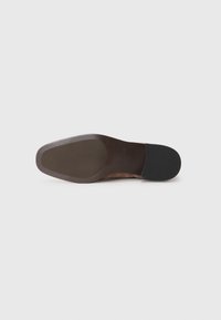 Suela de zapato de cuero marrón con un acabado suave, forma ligeramente curvada y tacón de goma negra. Las impresiones indican la marca y la talla.