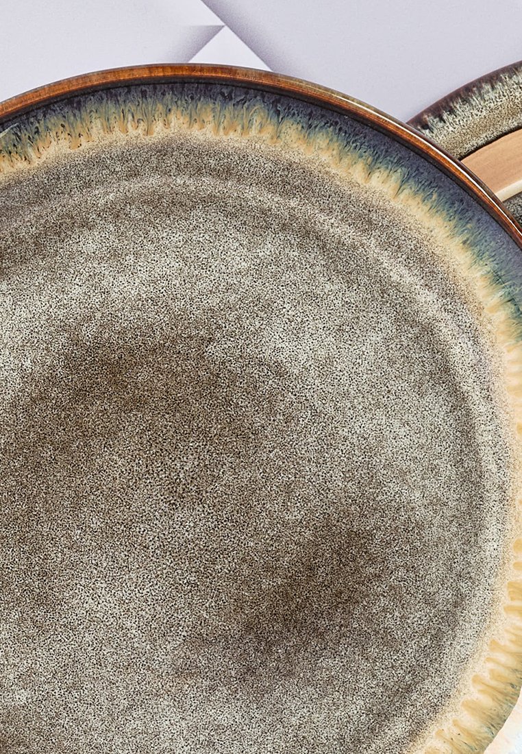Ceramiczny talerz o plamiście szarej-brązowej powierzchni, z teksturowanym brzegiem w gradientowych odcieniach niebieskiego i złota wokół krawędzi.