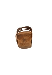 Brown sandal with cork footbed and soft suede strap. Side strap features a decorative bow. Flat sole and textured interior surface.