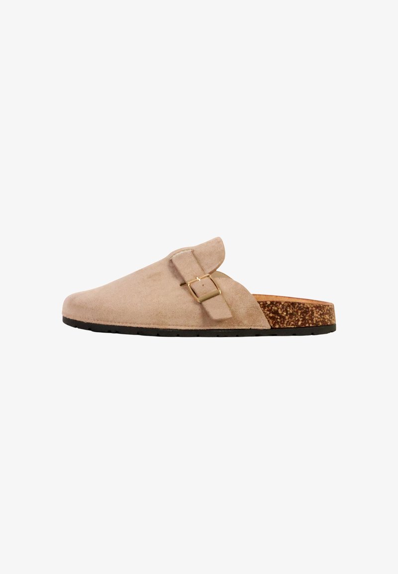 Sabot beige en daim à enfiler avec une lanière à boucle réglable, une semelle intérieure en liège et une semelle extérieure en caoutchouc noire, présenté de profil.