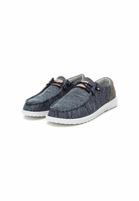 Zapatos sin cordones con una parte superior de punto texturizado de color azul oscuro, acentos en gris claro y una suela de goma blanca. Presenta dos cordones decorativos y un logo.