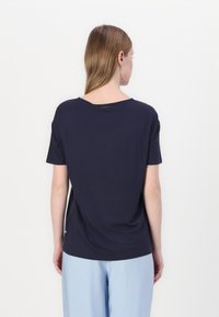 Camisetta a maniche corte blu navy con vestibilità morbida, scollo tondo e tessuto di cotone morbido. Presenta un piccolo logo sul retro vicino allo scollo.