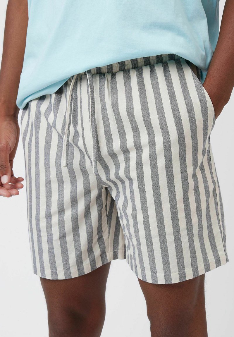 Pantalones cortos a rayas en tejido gris claro y crema, con cinturilla elástica, cordón ajustable y bolsillos laterales, que presentan un ajuste relajado.
