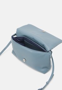 Borsa a mano in pelle azzurro chiaro con chiusura a patta, ferramenti argentati e una tracolla singola regolabile. L'interno presenta una fodera blu scuro e una tasca.