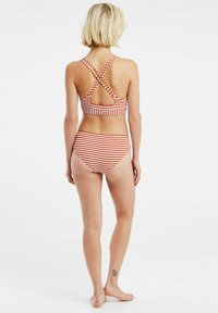 Gestreept bikini-set in de kleuren rood en wit. Het topje heeft gekruiste banden; de broekjes zijn hooggewaisted en hebben bijpassende strepen.