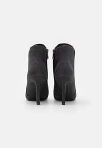 Schwarze Stoff-Unterziehstiefel mit strukturiertem Finish, hohen Stiletto-Absätzen und doppelten Reißverschlüssen an den Außenseiten.
