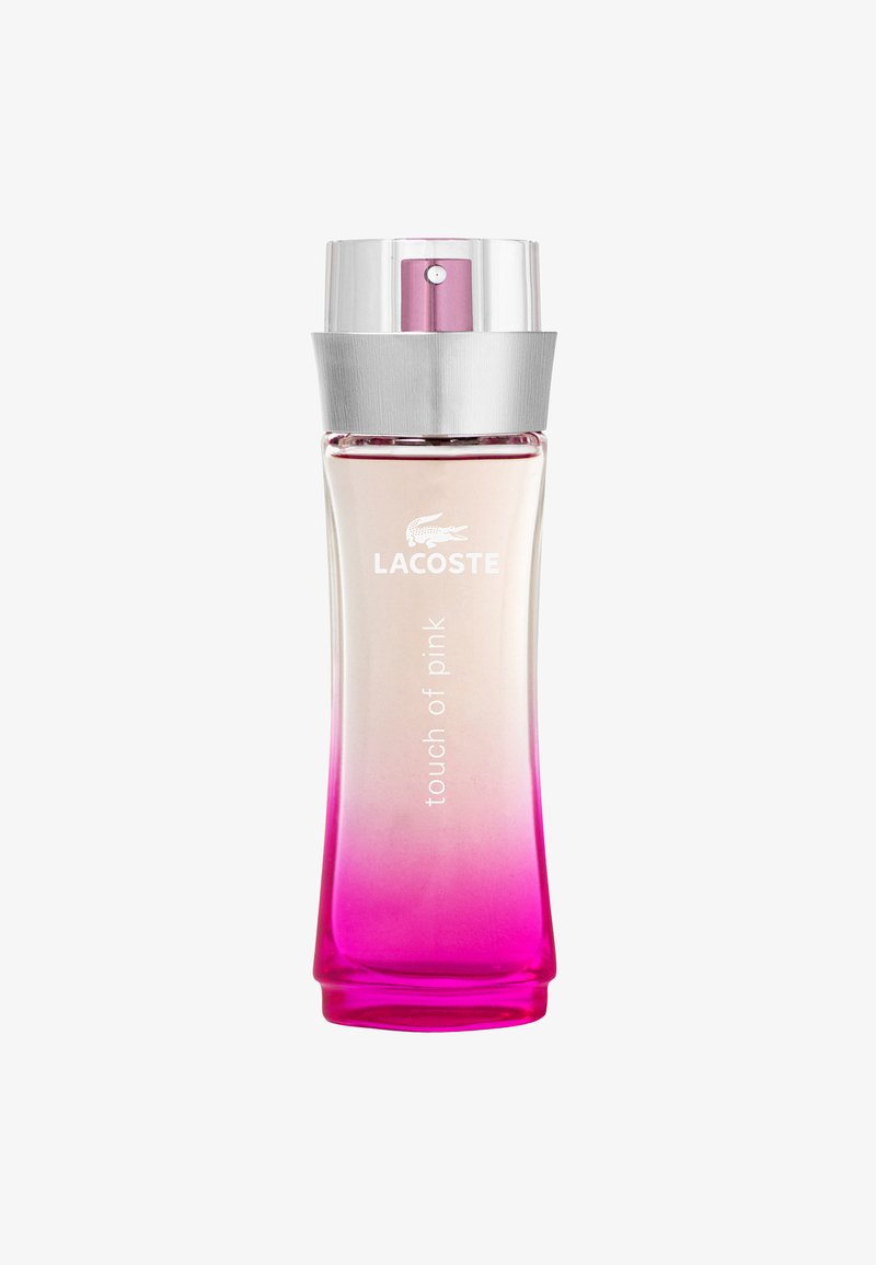 Flakon perfum Lacoste Touch of Pink ma przezroczysty gradient od przezroczystego do różowego, z srebrną nakrętką i wygrawerowanym logo.
