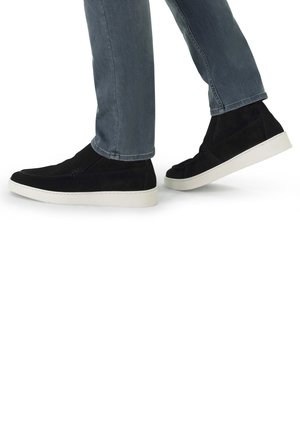 Black suede high-top sneakers with white rubber soles, worn with light blue jeans, showing a side view as the person walks.