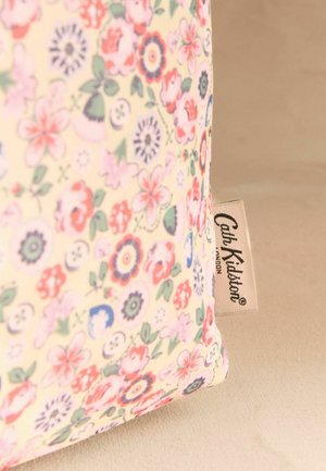 Čistilkasta tkaninska torbica z majhnim rožnatim, rdečim in modrim cvetličnim vzorcem ter oznako blagovne znamke Cath Kidston na bež površini.