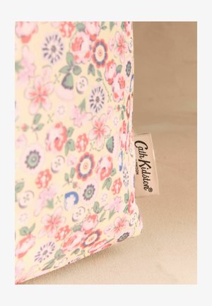 Čistilkasta tkaninska torbica z majhnim rožnatim, rdečim in modrim cvetličnim vzorcem ter oznako blagovne znamke Cath Kidston na bež površini.