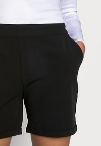 Zwarte shorts van een soepele stof, met zijzakken, gestikte zoom en een comfortabele pasvorm. De tailleband is elastisch voor extra comfort.